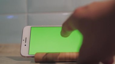 Yeşil ekranlı akıllı telefon ahşap tezgaha konur..