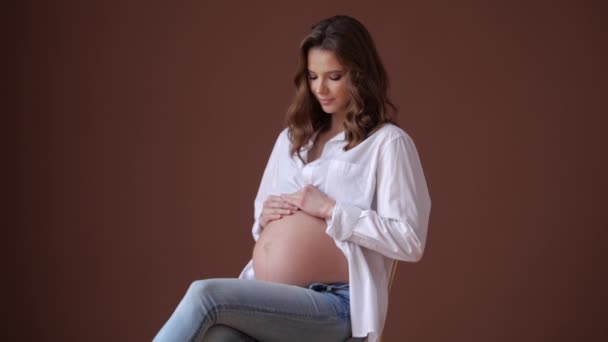 Zwangere vrouw zich gelukkig voelen thuis met bruine muur — Stockvideo