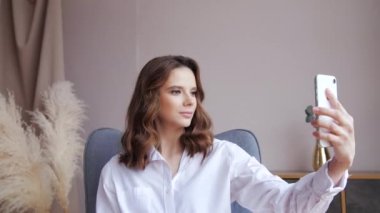 Yakın plan esmer hamile kadın evde hamile karnının selfie 'sini çekiyor.