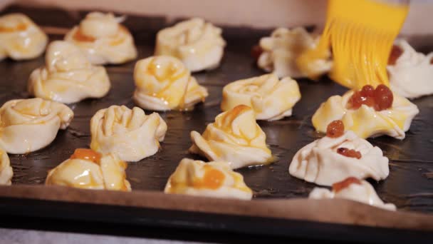 Сырые булочки на хлебном листе смазаны яичным желтком — стоковое видео