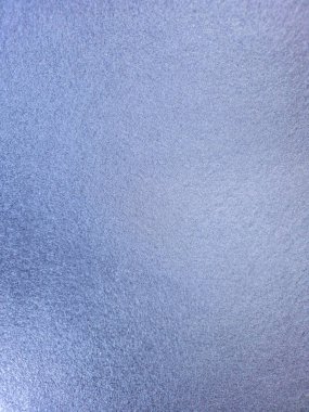 A macro shot of a light blue textured surface with a metallic sheen. The fine-grained, glittering background is perfect for design projects, festive themes, winter concepts, and abstract backdrops. The color is a cool, shimmering periwinkle or lilac.