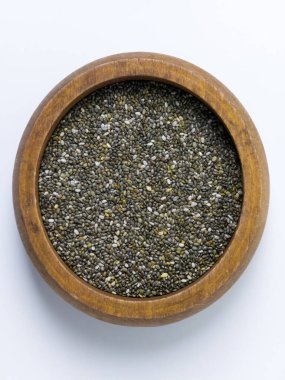 Top down view of raw, organic chia seeds in a round wooden bowl. This superfood is full of nutrients, fiber, and omega-3, perfect for a healthy diet, vegetarian, and vegan lifestyles. Isolated on a clean white background.