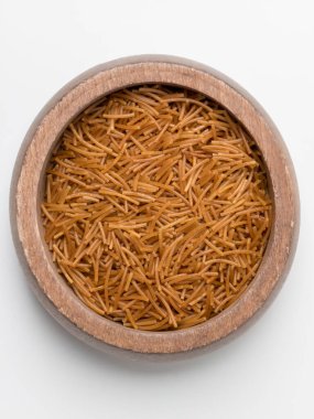 A top-down view of uncooked, toasted vermicelli fideo pasta in a round wooden bowl. The golden-brown pasta is ready to be used as an ingredient for cooking, especially in Mexican sopa de fideo. Isolated on a white background.