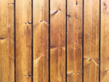 Detailed full-frame shot of a vertical wood paneling surface. The warm-toned timber planks show natural grain and texture, making an ideal rustic background or pattern for various design applications.