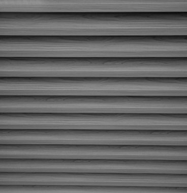Yatay panelleri olan bir duvarın siyah beyaz yakın çekimi. Yüzeyde belirgin bir ahşap doku var, doğrusal ve soyut bir desen oluşturuyor. Arkaplan, duvar kağıdı veya tasarım ve inşaat kavramları için ideal.