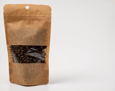 A stand-up pouch of roasted coffee beans in a brown kraft paper bag with a clear window. The resealable packaging is isolated on a clean white background, perfect for mockup designs and branding with ample copy space.