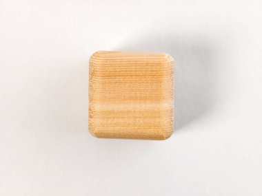 Yuvarlak köşeli tek bir dikdörtgen tahta bloğun yukarıdan aşağı manzarası. Tahtanın doğal yapısı ve dokusu görülebilir. Temiz beyaz bir arka planda, yumuşak bir gölgeyle izole edilmiş, basitliği, doğayı ve organik kavramları temsil ediyor..