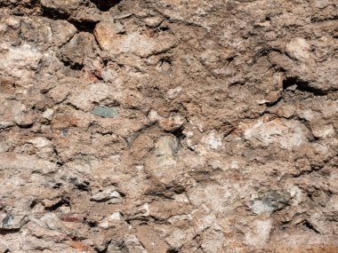 Eski ve yıpranmış bir duvar yüzeyinin detaylı görüntüleri. Kaba ve parçalanan dokuda, tasarım projeleri için mükemmel bir köy ve tarihi zemin oluşturan taşlar, kayalar ve eski havan toplarının karışımı yer alıyor..