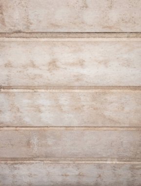 Kırsal ve yıpranmış bir yüzeye yakın çekim. Bej rengi taş veya beton paneller arasında derin oyuklar oluşturarak yatay olarak düzenlenir ve çizgili bir desen oluşturur. Doku pürüzlü ve benekli, arka planlar, örtüler veya mimari için mükemmel.