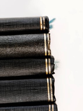 Omurgalarında altın folyo ayrıntıları olan eski, siyah ciltli kitapların yakın plan çekimi. Açık mavi bir yer imi görülebilir. Görüntü bir bilgi, tarih ve klasik edebiyat duygusunu çağrıştırıyor..