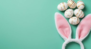 Paskalya bayramı kompozisyonu, altın çizgili beyaz yumurtalar ve nane yeşili arka plan üzerinde yumuşak pembe bir tavşan kulaklığı ve metin için boş kopya alanı..