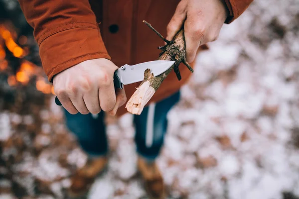 A man uses a knife to whittle a stick out hiking — Stock Photo, Image