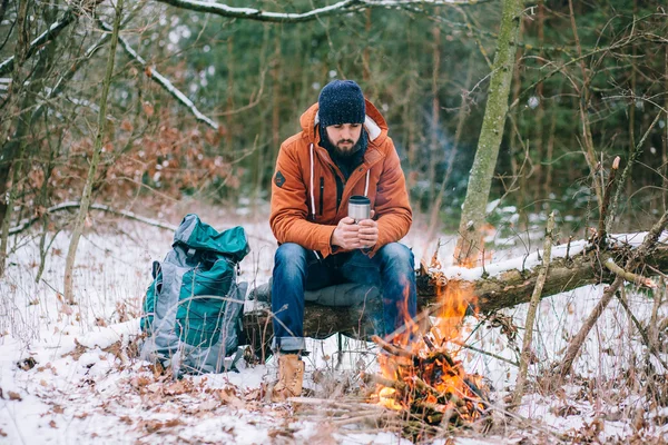 Путешественник разогревается у костра в зимнем лесу — стоковое фото