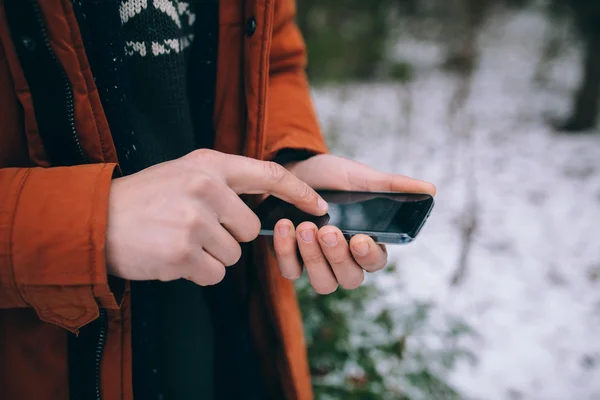 Man on winter field holding mobile phone — Stock Photo, Image