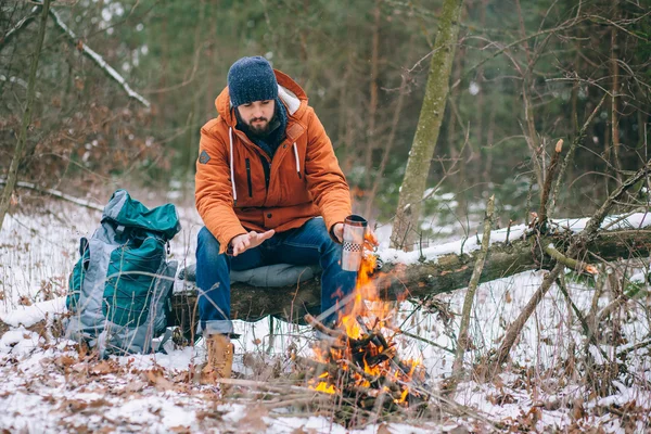 Voyageurs réchauffés par le feu dans la forêt d'hiver — Photo