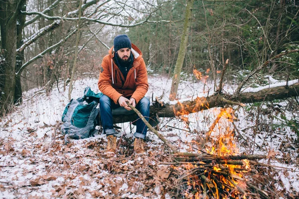 Reisender wärmt sich am Feuer im Winterwald auf — Stockfoto