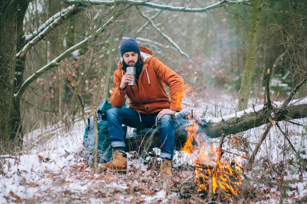 Viajero calentándose junto al fuego en el bosque de invierno —  Fotos de Stock