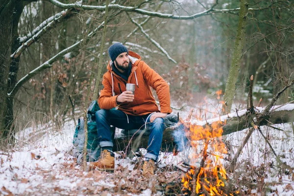 Reisender wärmt sich am Feuer im Winterwald auf — Stockfoto