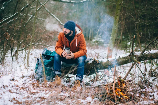 Traveller, nagrzewa się przy ognisku w lesie zimą — Zdjęcie stockowe