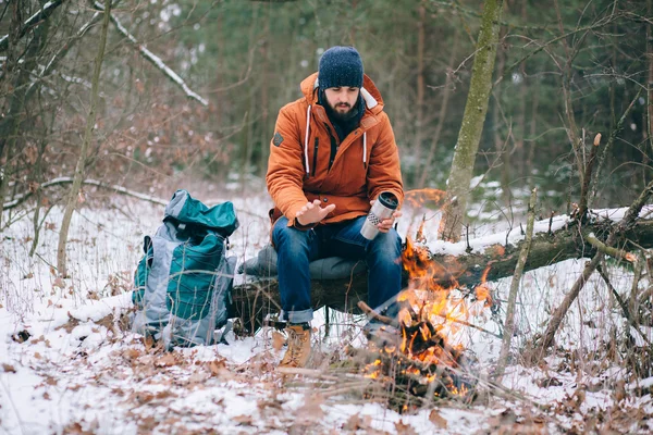 Reiziger warming-up door de brand in de winter forest — Stockfoto