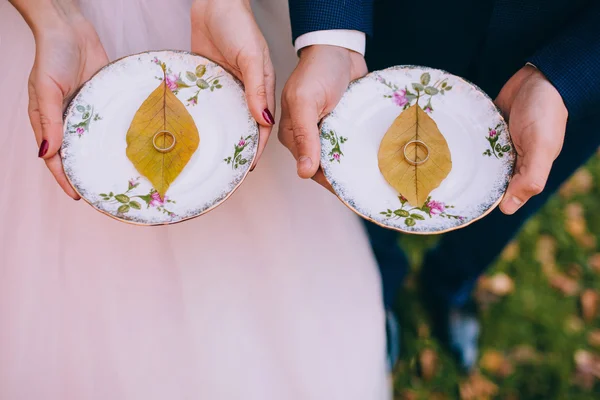 Pareja con anillos de boda en platos —  Fotos de Stock