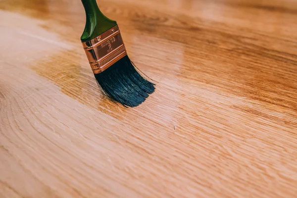 Verniciatura di un pavimento in legno con pennello — Foto Stock