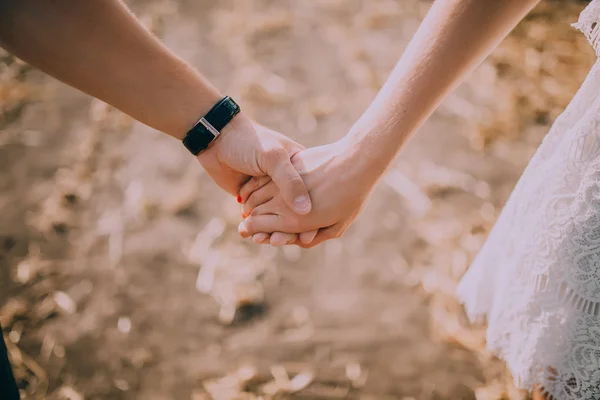 Koppel hand in hand op het strand — Stockfoto