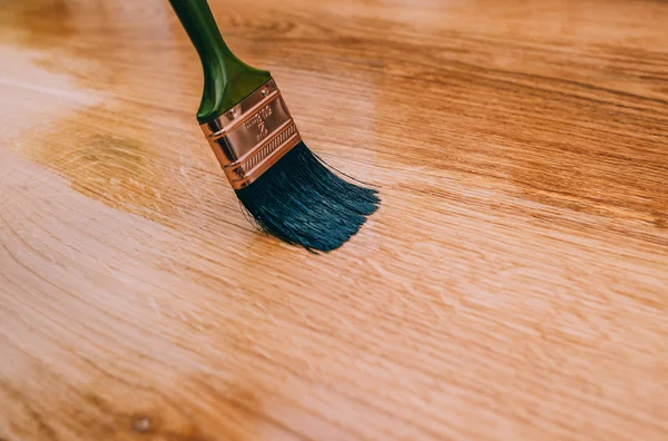 Varnishing a wooden floor using paintbrush — Stock Photo, Image