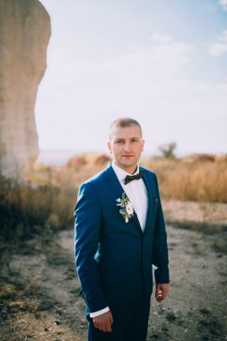 kayalar bir arka plan karşı poz damat