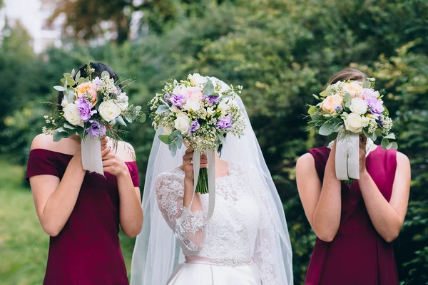 Noiva e damas de honra segurando buquês — Fotografia de Stock