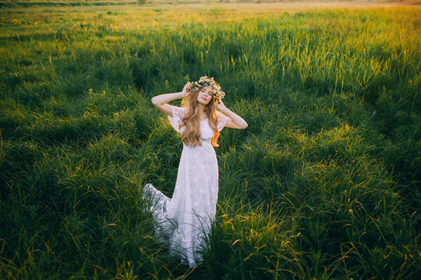 Young girl in a beautiful long white dress in the meadow