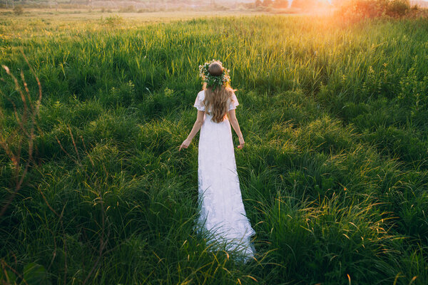Young girl in a beautiful long white dress in the meadow