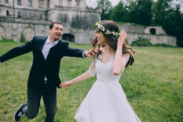 Newlyweds running by old castle — Stock Photo, Image