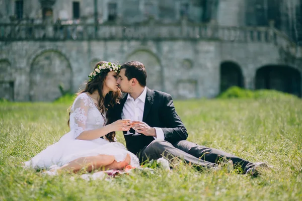 Newlyweds kissing by old castle — Stock Photo, Image