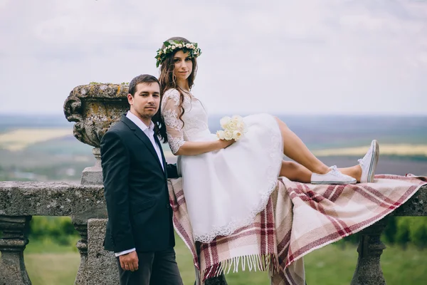 Newlyweds sitting by the stairs of old castle — Stock Photo, Image