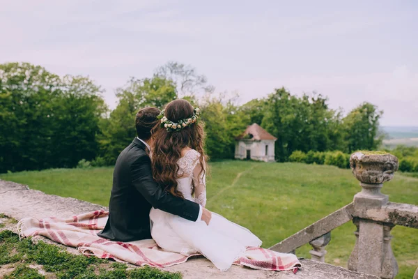 Newlyweds sitting by the stairs of old castle