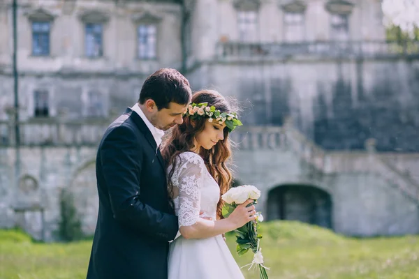 Newlyweds embrace by the old castle — Stock Photo, Image