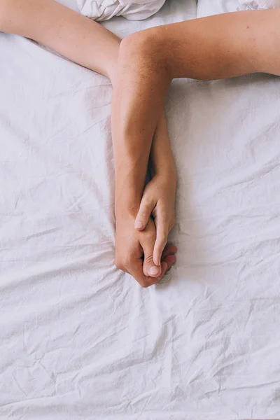 Hands of a couple inn a bed — Stock Photo, Image