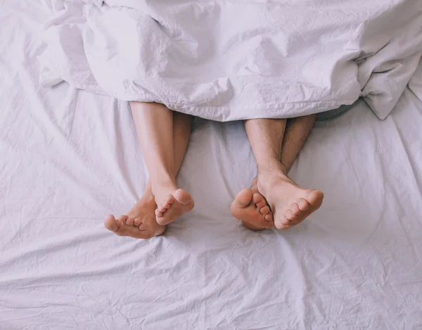 Feet of couple side by side in bed — Stock Photo, Image
