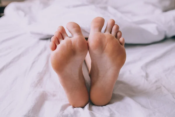 Lidské nohy v posteli — Stock fotografie