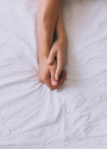 Mãos de um par pousada uma cama — Fotografia de Stock