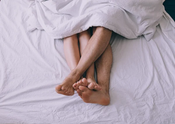 Pies de pareja lado a lado en la cama — Foto de Stock