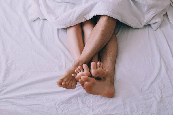 Feet of couple side by side in bed — Stock Photo, Image