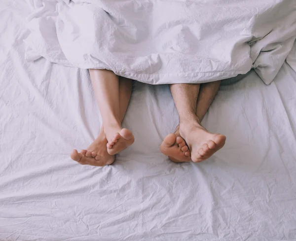 Feet of couple side by side in bed — Stock Photo, Image