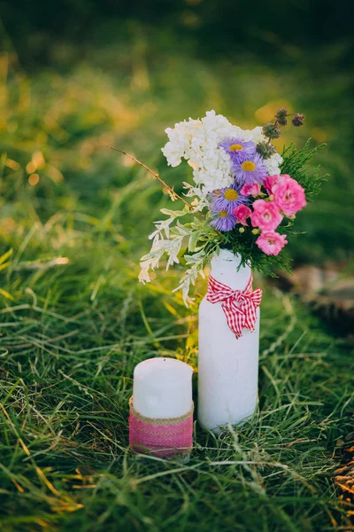 Цветы и свечи на лугу — стоковое фото