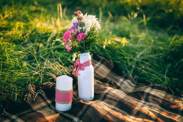 Flowers and candle in meadow — Stock Photo, Image