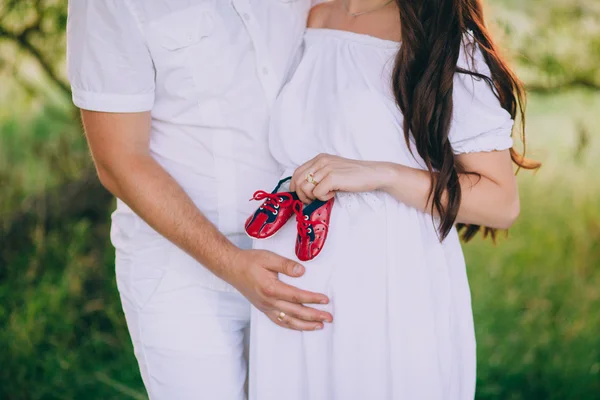 Pregnant couple with baby shoes