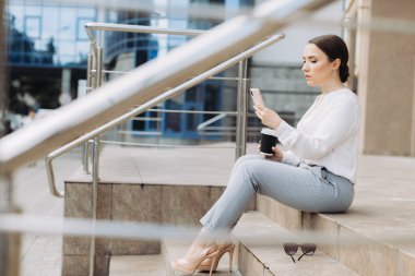 İş kadını iş merkezinin arka planında telefonunu kontrol ediyor.