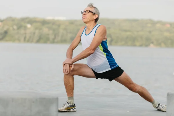 senior man is engaged in sports on the lake embankment. High quality photo