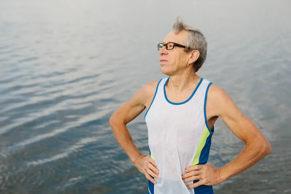 Homem sênior está envolvido em esportes no dique do lago — Fotografia de Stock